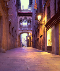 Illuminated medieval street Carrer del Bisbe with Bridge of Sighs in Barri Gothic Quarter in Barcelona, Catalonia, Spain