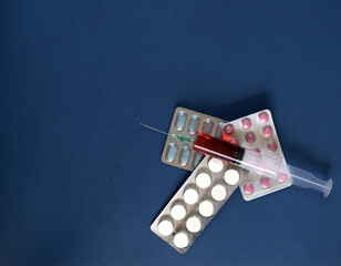 packaging of pills and syringe on a blue background