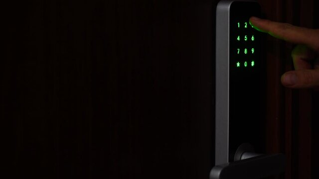 Close-up a man hand entering unlocking combination on digital security lock and opens a door of a house