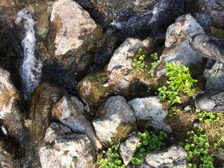 legs in boots on the stones of a mountain river