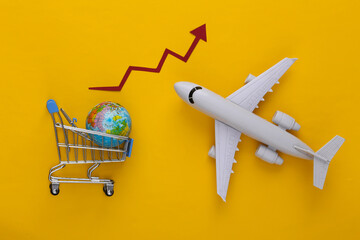 Global supermarket. Increased international shipping. Shopping trolley, globe and plane with growth arrow on yellow background