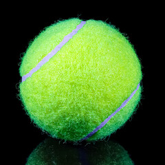 Fluorescent yellow lawn tennis ball on black background