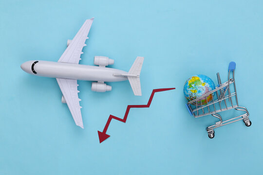 International shipping. The fall of global shopping. Supermarket trolley with a globe, airplane, falling arrow tending down on blue background.
