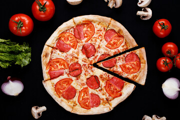 Pizza with ingredients on a black background. Top view.