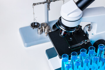 Close up of laboratory microscope with set of test tubes with blue liquid