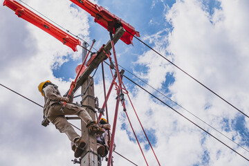 Two linesmen use insulated equipment to repair and maintain high-voltage distribution systems. The operation is done without power outage. Is a risky job, the operator must be trained.