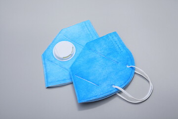 Two folded blue N95 masks against a gray background
