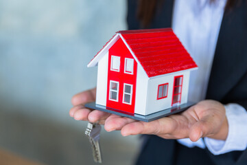 The keys and the red house are in the hands of real estate agents, real estate sales ideas, rental housing, buying apartments, selling apartments.