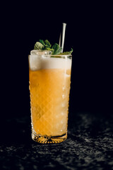 Orange cocktail with mint in a beautiful glass with ice on a dark background