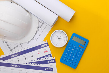 Construction helmet, blueprint and calendar, calculator and clock on yellow background....