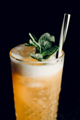Orange cocktail with mint in a beautiful glass with ice on a dark background