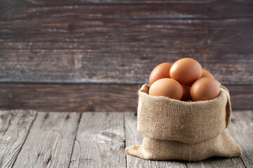 Close-up view of raw eggs in egg Sack on Brown wooden background