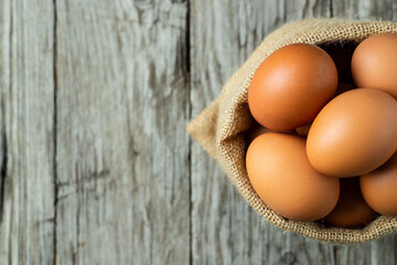 Close-up view of raw eggs in egg Sack on Brown wooden background