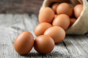 Close-up view of raw eggs in egg Sack on white wooden background