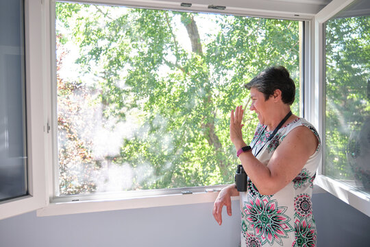 Woman With Binoculars Greeting To A Neighbor Through The Window