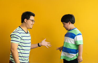 the rock-paper-scissors gesture of Asian father and child, successful cooperation of generations, yellow  background
