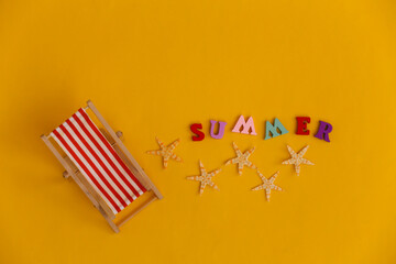 Mini beach deck chair and starfish on yellow background. Word summer. Symbol of beach holidays, resort.  Relax, Summer minimal concept. Top view