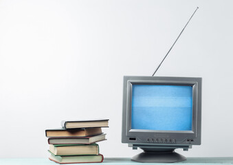 Antenna old-fashioned retro tv receiver and stack of books on white wall background