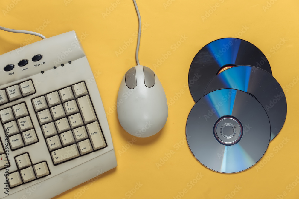 Poster old-fashioned retro keyboardб cd's and pc mouse on yellow background. top view