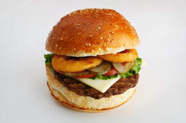 Juicy burger with onion rings, cucumbers, lettuce, cheese on a white background