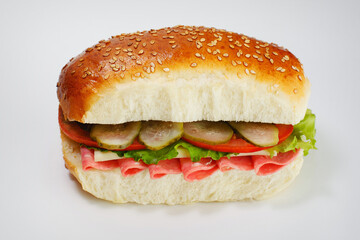 Juicy sandwich with cucumbers, lettuce, cheese and bacon on a white background