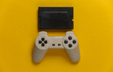 Gamepad with cartridge on a yellow background. Retro entertainment, gaming. Top view