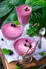 Berry mousse in glass vases on a wooden background in the garden.