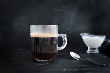 transparent mug with coffee and milk on a black background