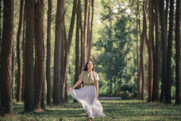 Naklejka premium women asian girl walking in the natural park pine forest alone nature people concept.