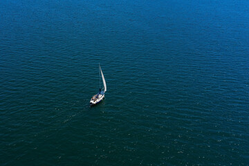 aerial view of a lonely white sailing yacht at sea