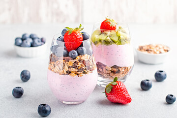 Chia seeds layered pudding with granola, blueberry and strawberry in glasses. Yogurt with chia seeds, berries, kiwi and muesli for healthy breakfast, copy space. Perfect for summer snack or dessert