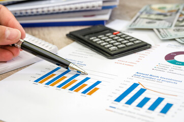 female hand with a pen points to a business chart. Income analysis. Business concept. Close-up.
