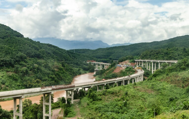 Fototapeta na wymiar Belt and Road Initiative, One Belt One Road (OBOR) corporate - Chinese Xiaomo Highway bridge under construction in the green jungle between Lao border town Boten and Mengla, Yunnan, China