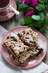 Sweet cake with cherry rose arenas and streusel on a wooden background. Rustic style.