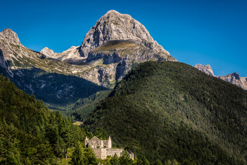 Fototapeta na wymiar Fort Predel and famous Mangart mountain in background. Amazingly beautiful Slovenia landscape nature. Hills covered with forest. Julian Alps in summer season