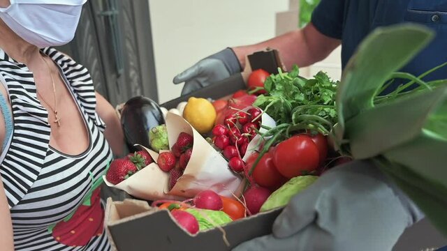 Delivery Man Wearing Blue T-shirt And Black Mask Giving To A Woman Black Fruit And Vegetables Box During Covid-19 Pandemic, Slow Motion