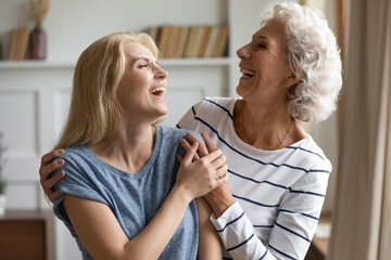 Cheerful lively mature mother and grown up daughter laughing enjoy funny conversation, telling jokes and anecdotes, women having wonderful sense of humor, amuse each other at meeting at home concept