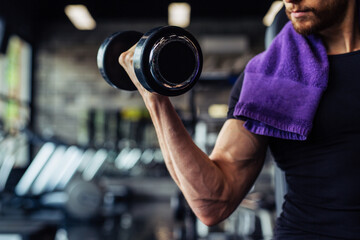 Hand holding dumbbell.Close up.Muscular arm in the gym.