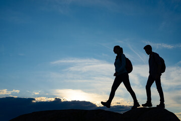 Young Happy Travelers Hiking with Backpacks on the Rocky Trail at Summer Sunset. Family Travel and Adventure Concept. © Maksym Protsenko
