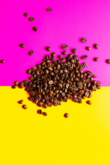 aromatic Roasted coffee beans pile pink and yellow background. top view