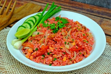Authentic Thai old style fried rice in red sauce served with spring onion, cucumber slices and lime.