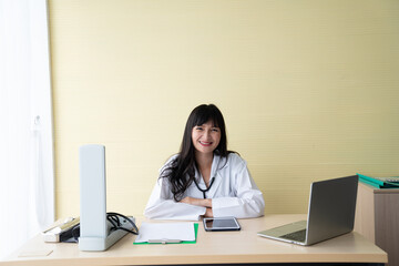 Happy Female Doctor sit in examination room / copy space