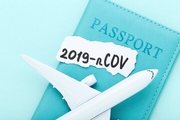 Text 2019-nCov with passport and airplane model on blue background