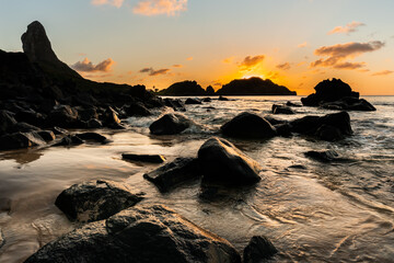 Beautiful Sunset view on the rocks formation with Morro do Pico in the background at Cachorro Beach, Fernando de Noronha Marine National Park , a Unesco World Heritage site, Pernambuco, Brazil