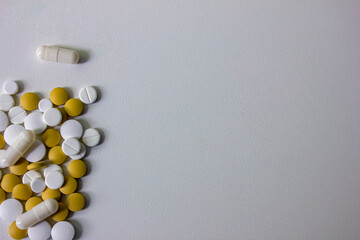 A lot of white and yellow pills and capsules on a white background