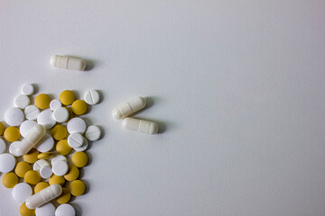 A lot of white and yellow pills and capsules on a white background