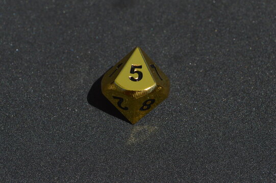 Gold metallic d10 ten sided dice on foam surface