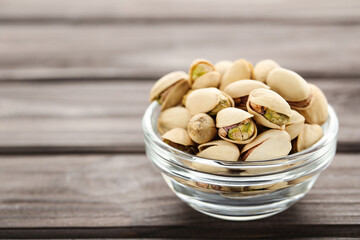 Tasty pistachios in bowl on wooden table