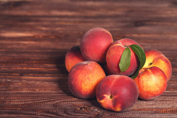 Fototapeta na wymiar Fresh peaches with green leafs on brown wooden table