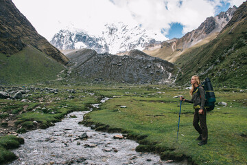 Experienced young woman tourist with backpack admiring amazing scenery of Salkantay mountain during...